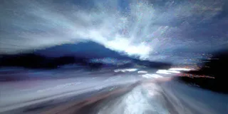 Motion blur photograph of a mountain road at night with scattered lights