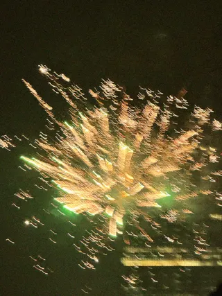 Motion blur photograph of golden fireworks bursting against a dark night sky