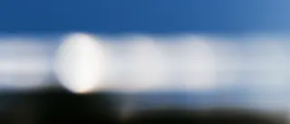 blurred long exposure of the sun repeating in ghost trails across a deep blue sky above a dark horizon