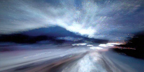 Motion blur photograph of a mountain road at night with scattered lights