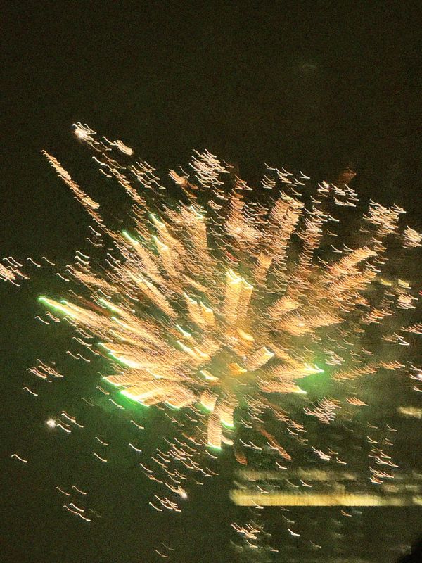 Motion blur photograph of golden fireworks bursting against a dark night sky