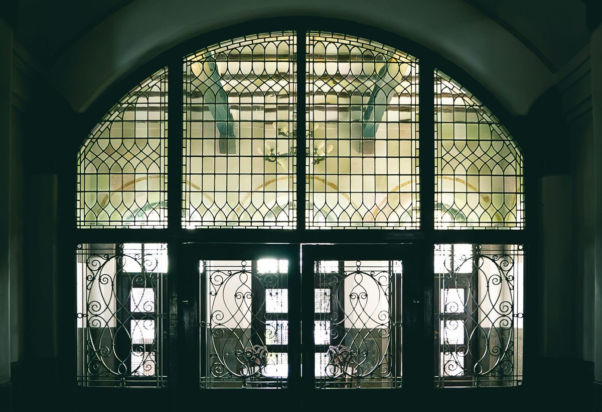 A leaded glass window looks onto large open space