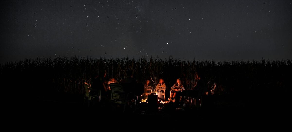 Storytellers around campfire below clear night sky