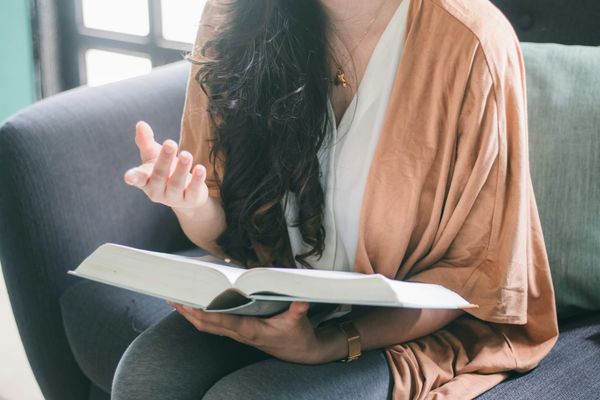 A person sitting on an armchair with a book in their hands