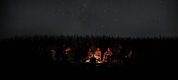 Storytellers around campfire below clear night sky