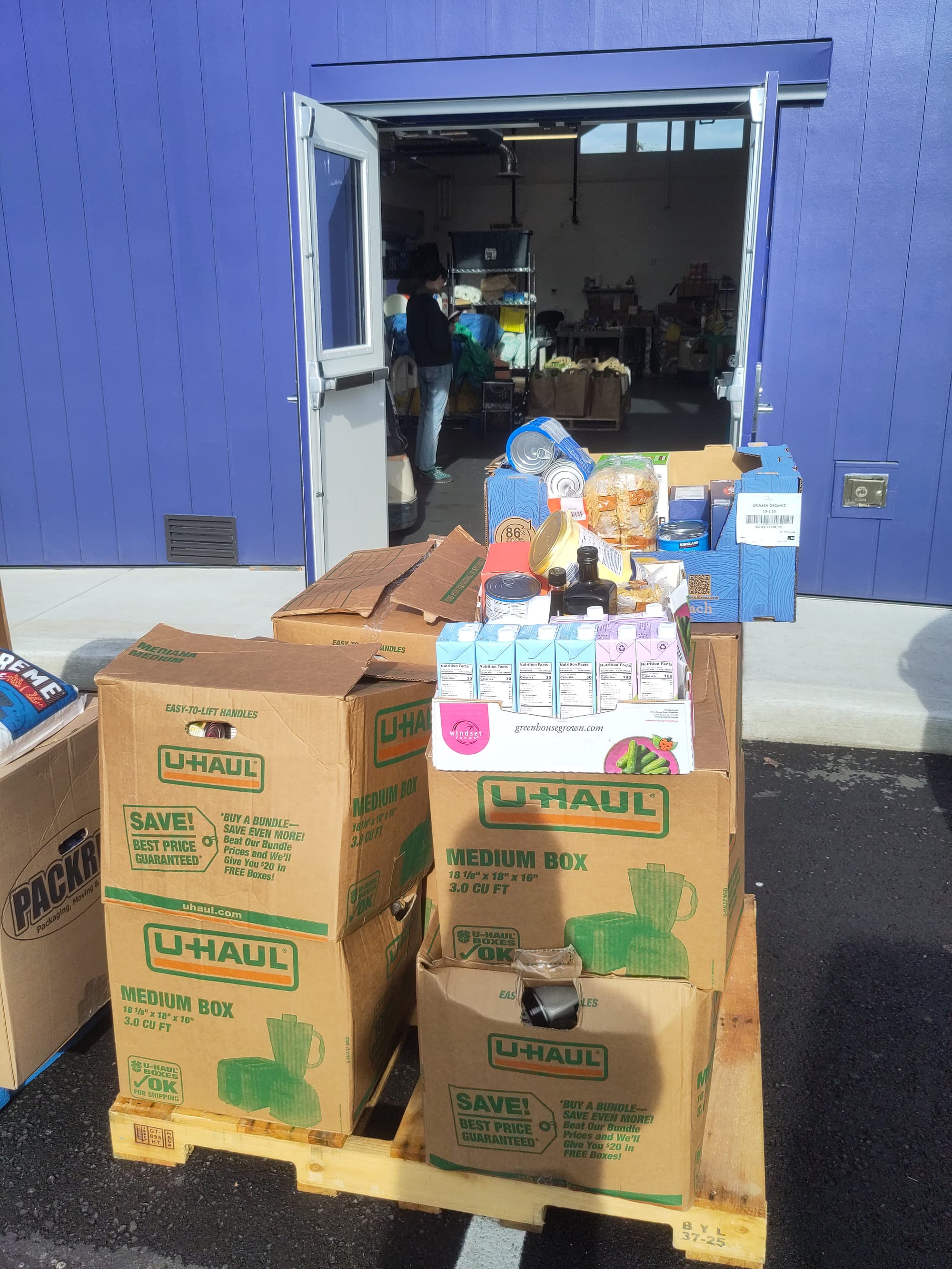 U-Haul boxes full of cans and cartons of food sit on a wooden pallet