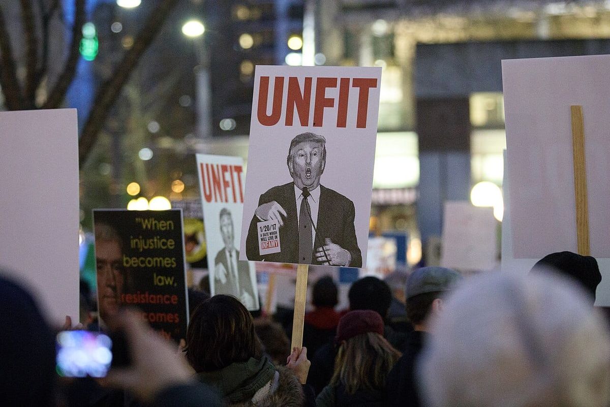 At a night time protest in Seattle's Westlake park, protesters hold signs including one of Donald Trump that reads "UNFIT."