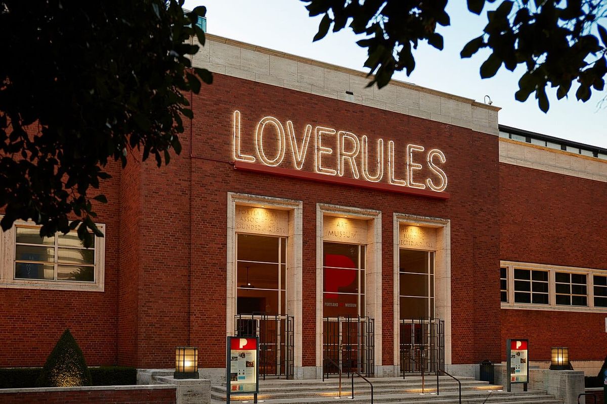 The front facade of the Portland Art Museum with a neon art sign over the door that read "LOVERULES"