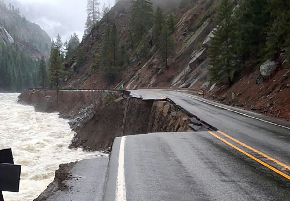 A section of highway is washed away next to a raging whitewater river