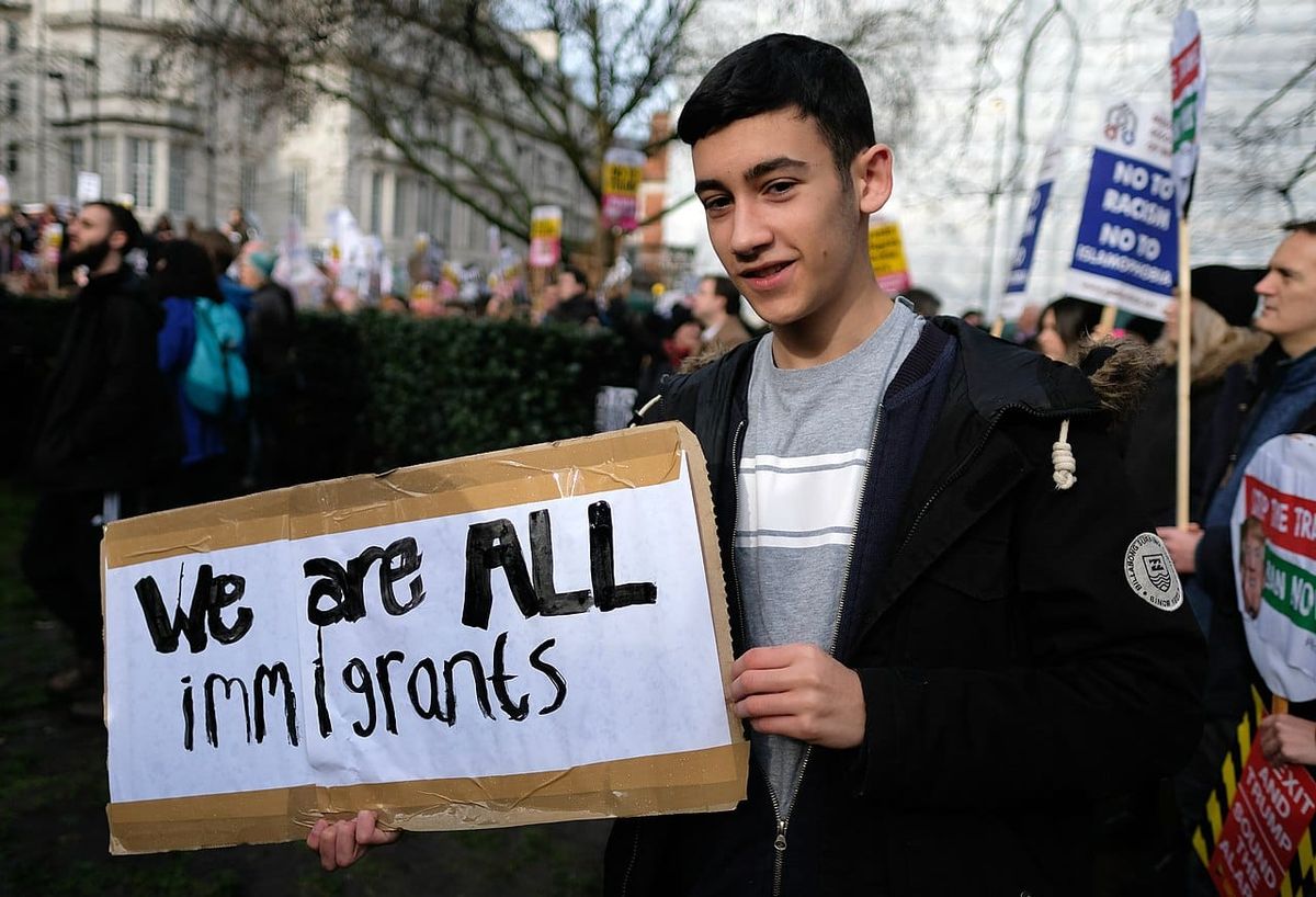 A protester at a rally holds a sign that reads: we are all immigrants