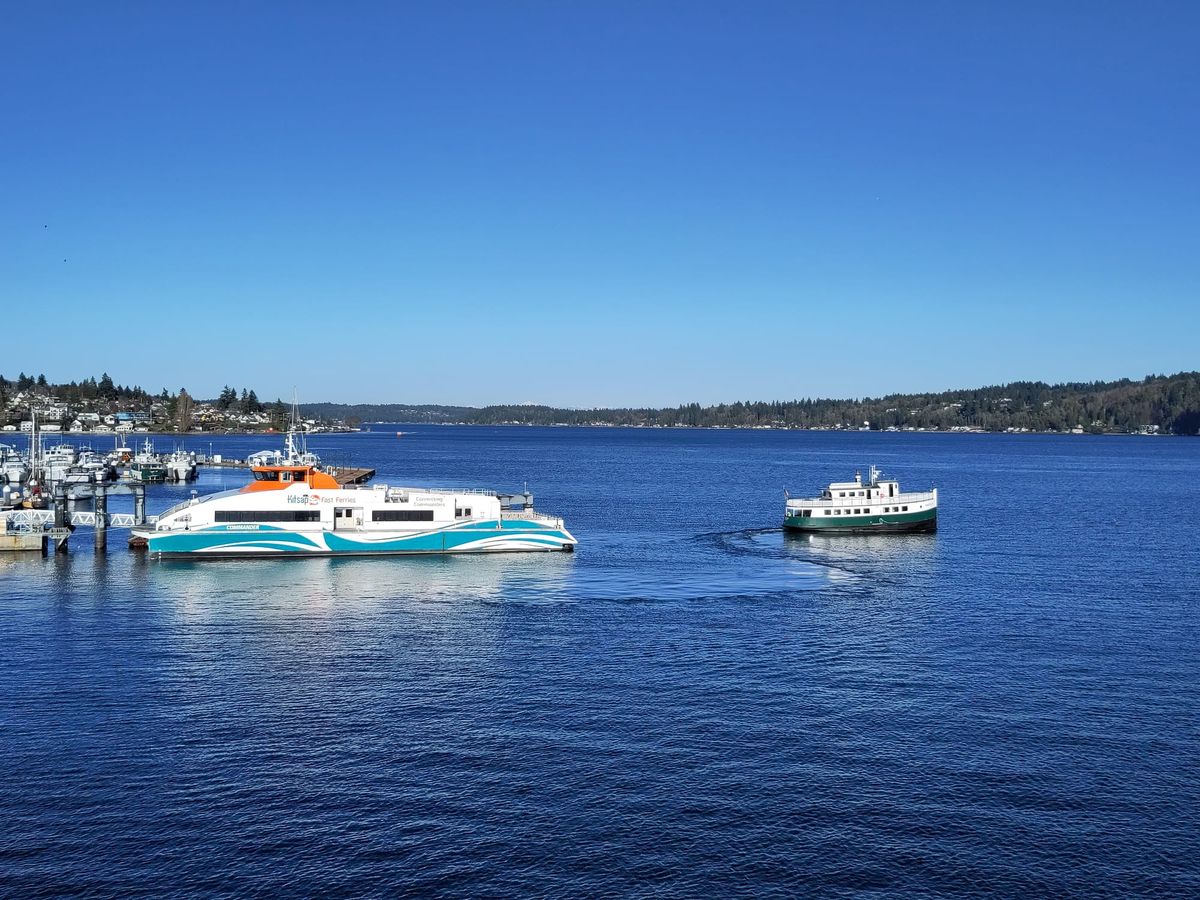 A modern passenger ferry and a tiny older diesel-driven ferry seen on Puget Sound