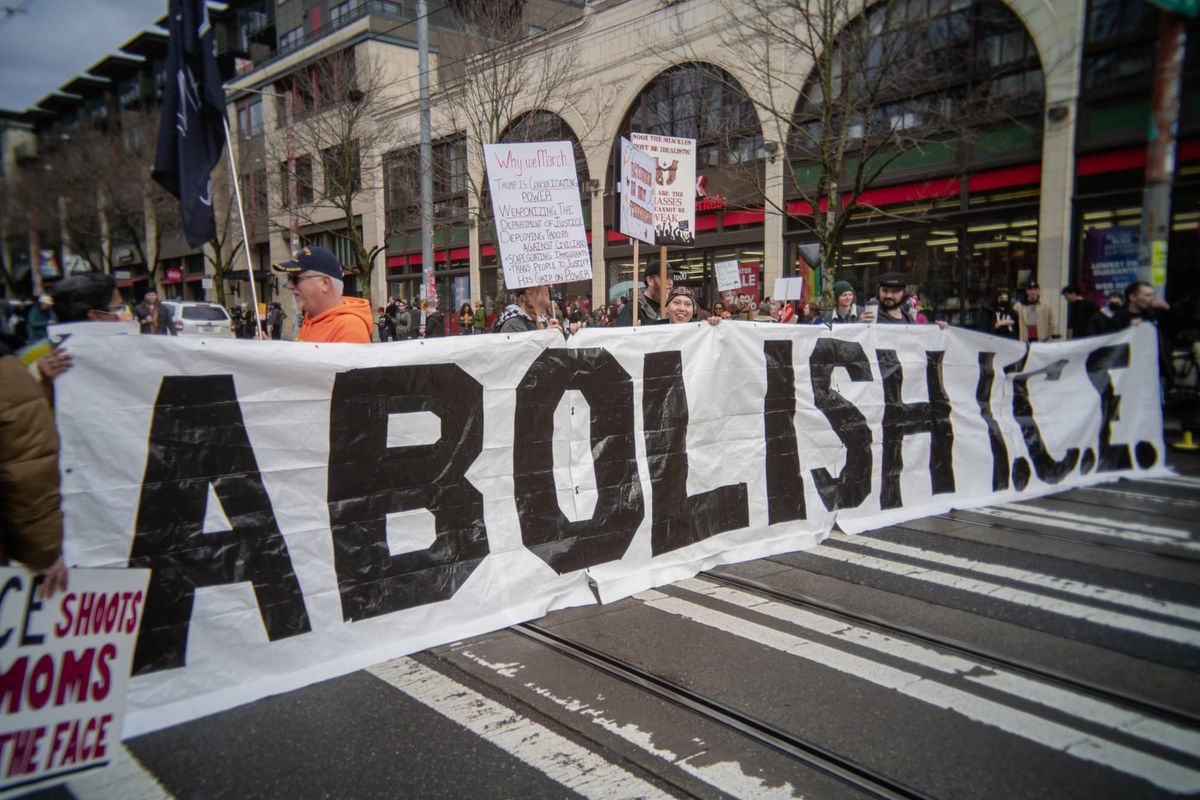 Protesters hold a large banner that reads: abolish ICE