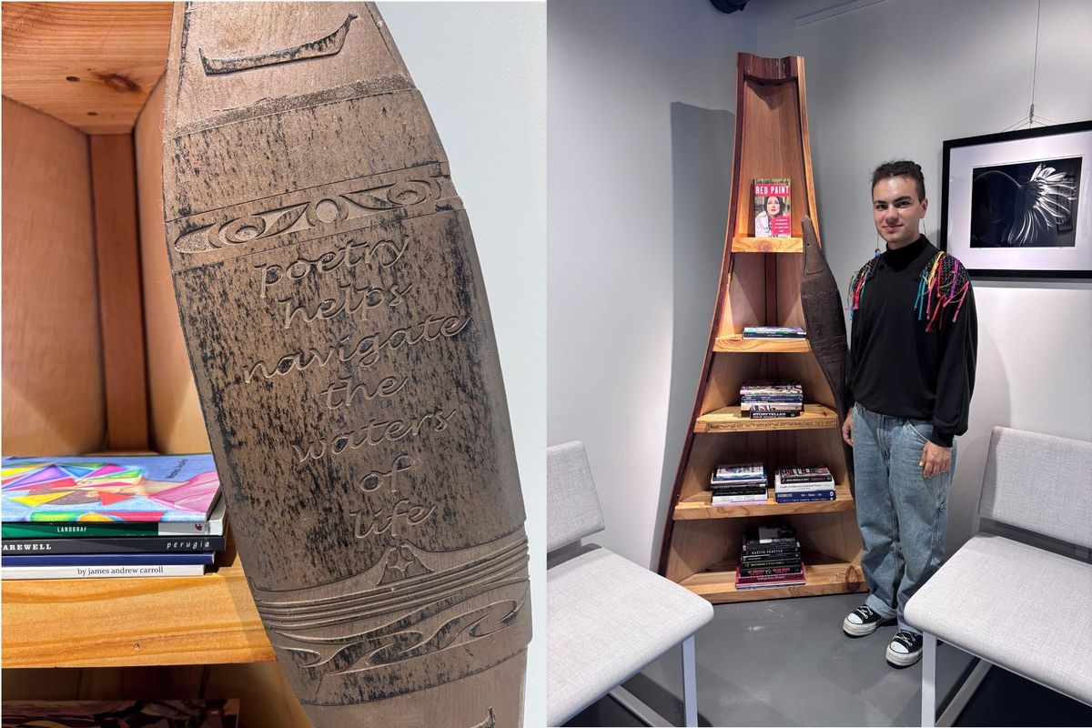 A person stands next to a bookcase shaped like the prow up and upended canoe. A paddle has the inscription: poetry helps navigate the waters of life
