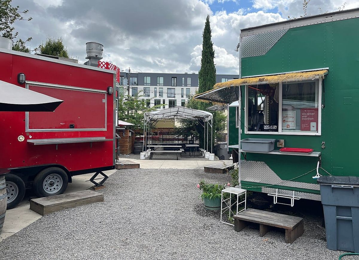 Two food carts and some empty tables in courtyard.