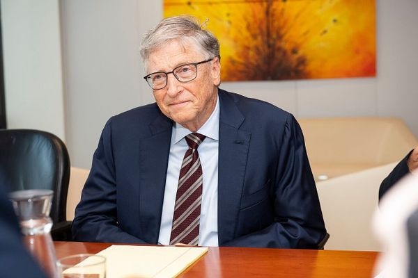 Bill Gates sits at a desk.