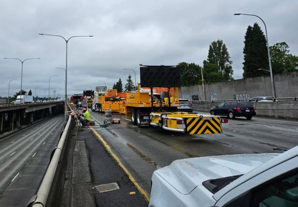 workers use orange-painted machinery to repave a stretch of highway