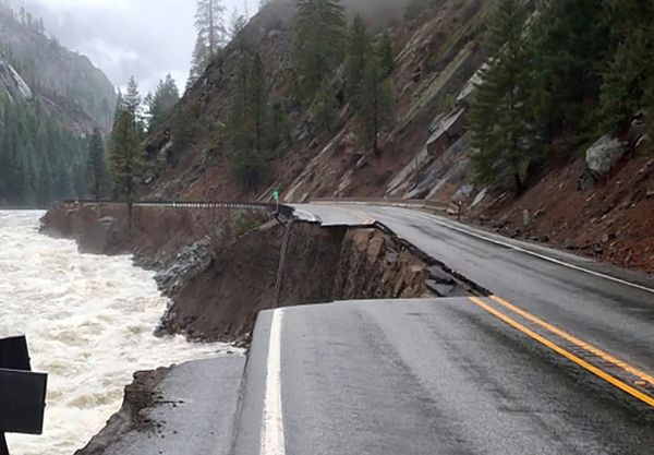 A section of highway is washed away next to a raging whitewater river