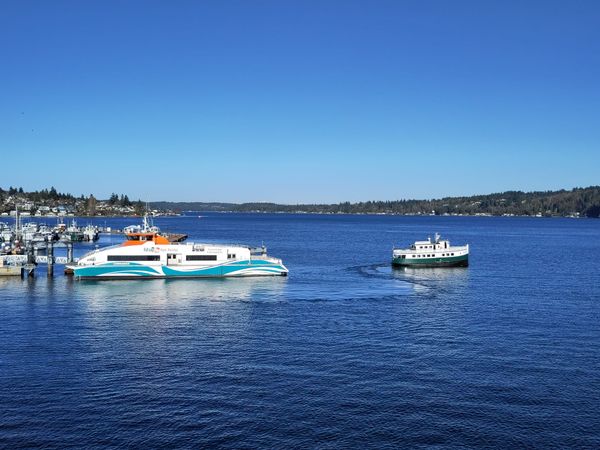 A modern passenger ferry and a tiny older diesel-driven ferry seen on Puget Sound