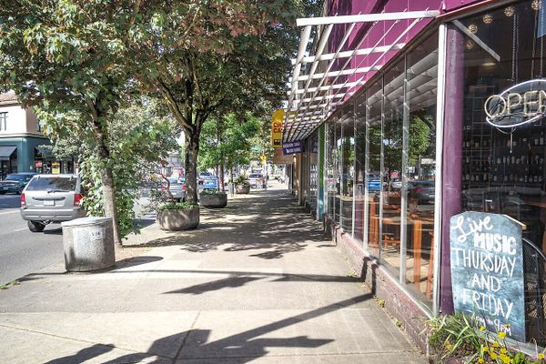 Various shops on a sidewalk, with a sign reading Live Music Thursday and Friday in one window.