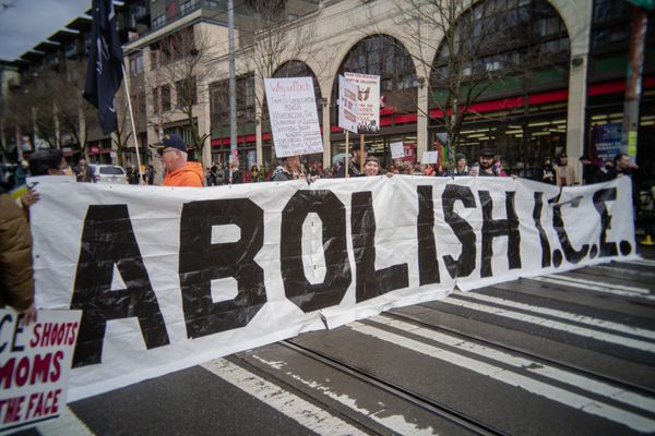 Protesters hold a large banner that reads: abolish ICE