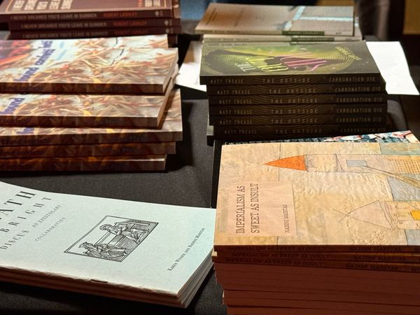 Stacks of books, including one calle Imperialism as Sweet As Insult by Nadine Maestas.