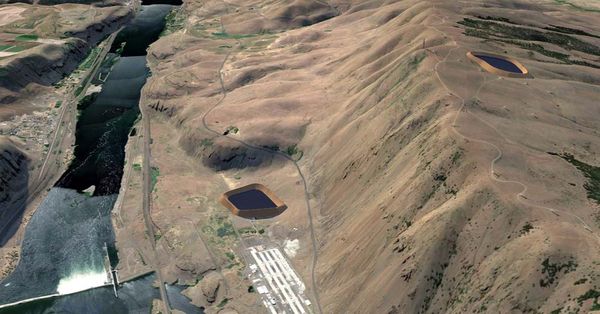 A gravity-fed energy generation project alongside a dam in a dry landscape.