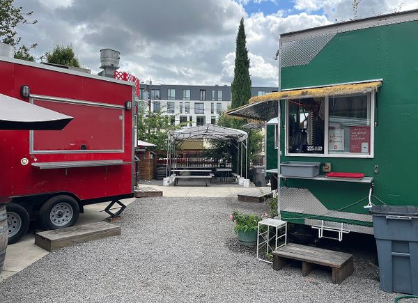 Two food carts and some empty tables in courtyard.