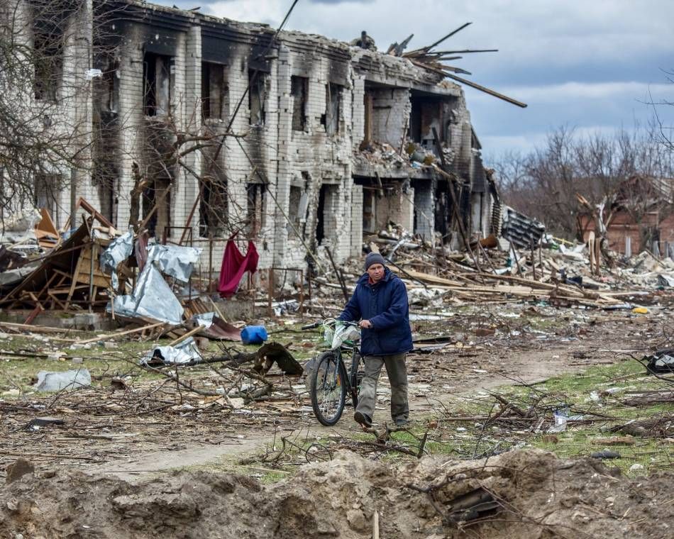 A man pushes his bicycle past the ruins of Novoselivka, a Ukrainian village near Chernihiv, in April