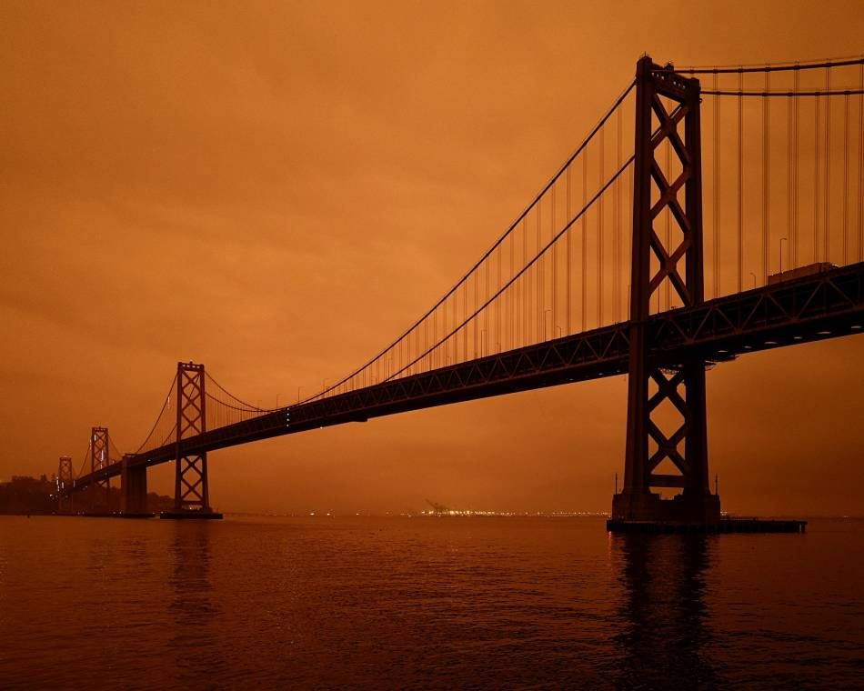 San Francisco's Bay Bridge under an orange sky darkened by smoke from California wildfires