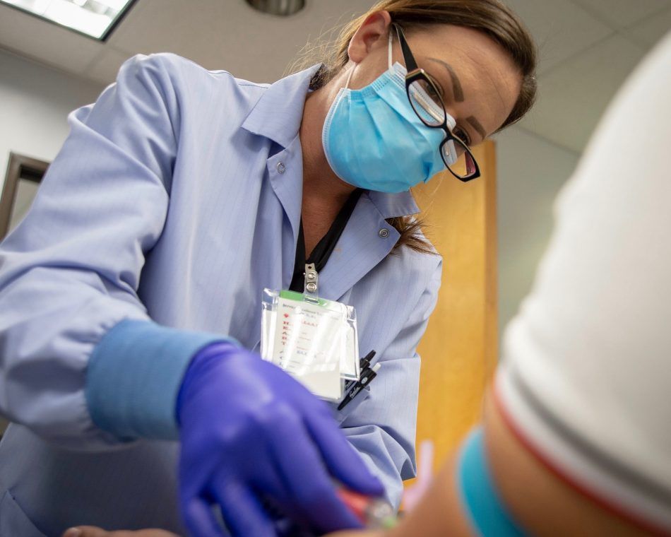 A medical assistant at a U.S. Navy health clinic draws a patient’s blood for Phase III trials of a COVID-19 vaccine