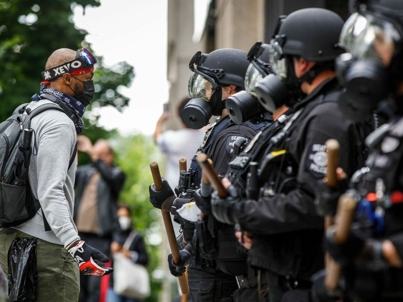 A U.S. protestor speaks with a line of police officers during the George Floyd protests in Seattle, Wash. in late May