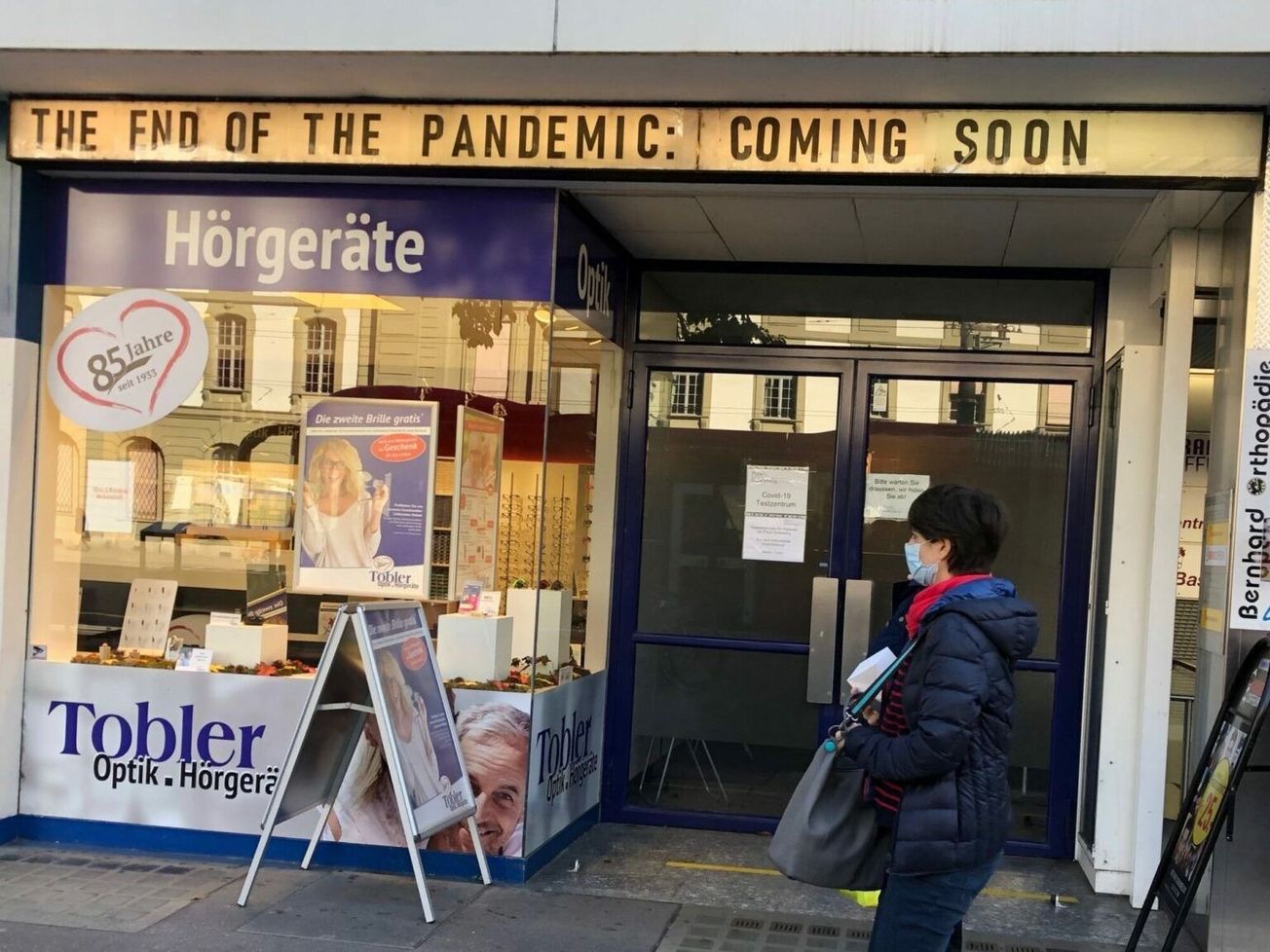 A woman in a mask passes a closed Swiss movie theater-turned-COVID-19 testing center in Bern