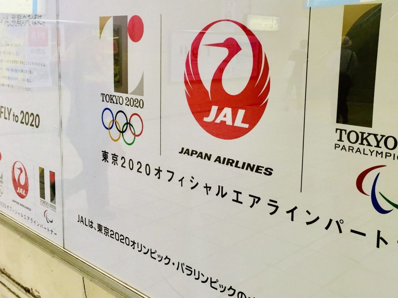 Pedestrians reflected in Tokyo ads for the Summer Olympic and Paralympic Games