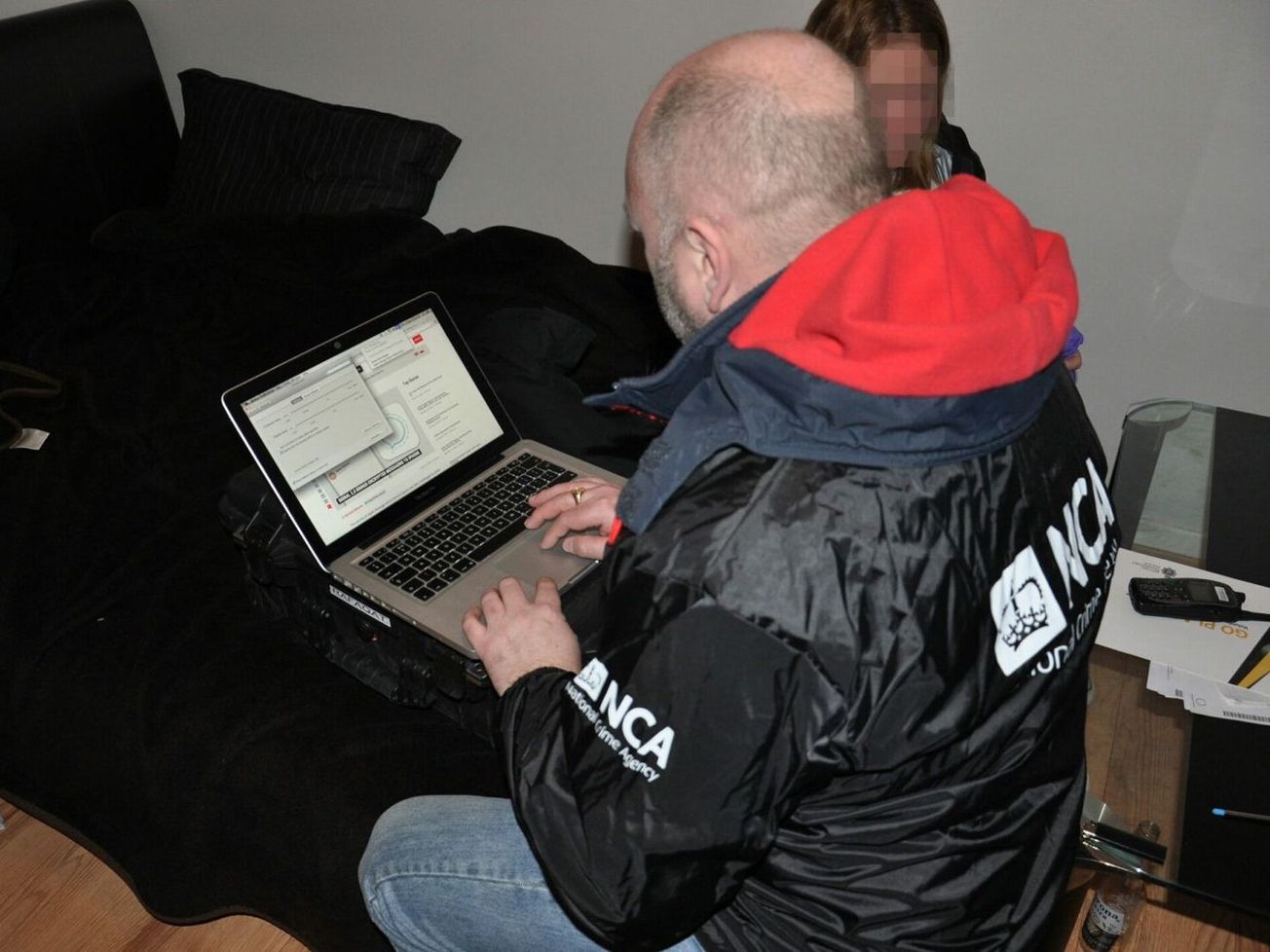 An officer with the U.K.'s National Crime Agency triages a seized computer for evidence of criminal activity