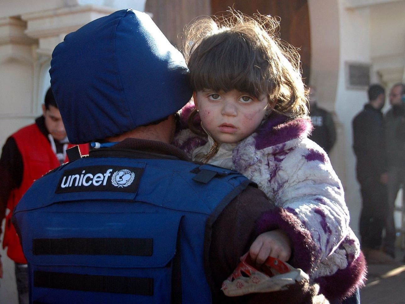 A UNICEF aid worker carries a child at a shelter in Homs, Syria