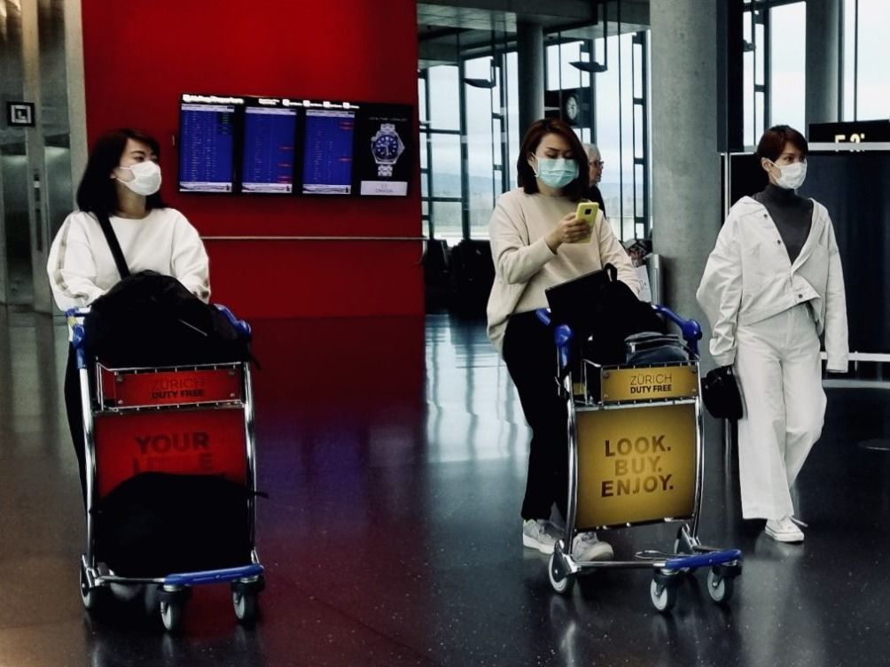 Travelers wearing protective masks at Zurich Airport on March 12, 2020
