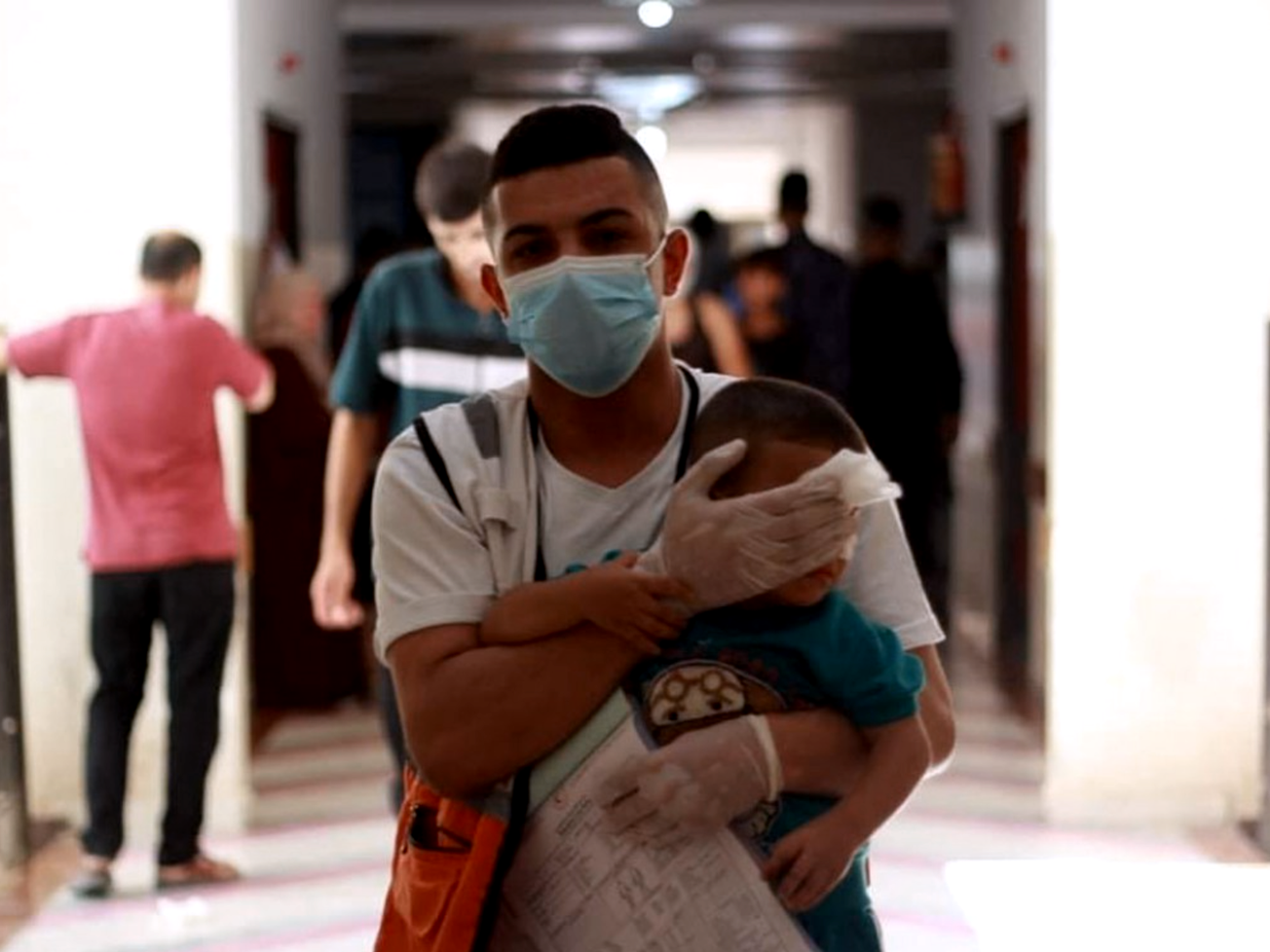 An aid worker comforts an injured child in Gaza