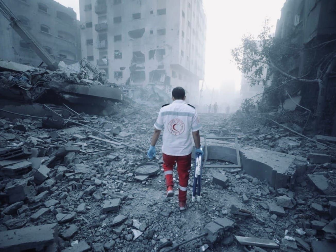 An EMT with the Palestine Red Crescent Society walks through rubble in Gaza