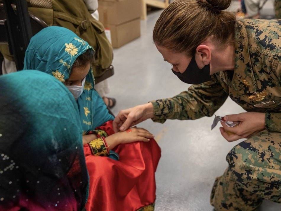 An Afghan girl preparing to get a COVID-19 booster shot