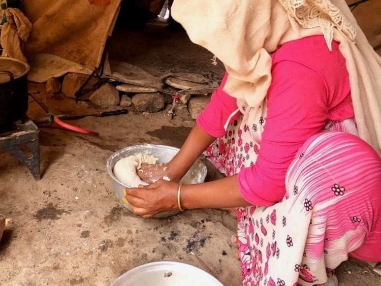 A mother prepares lunch for her family at a refugee camp in Yemen