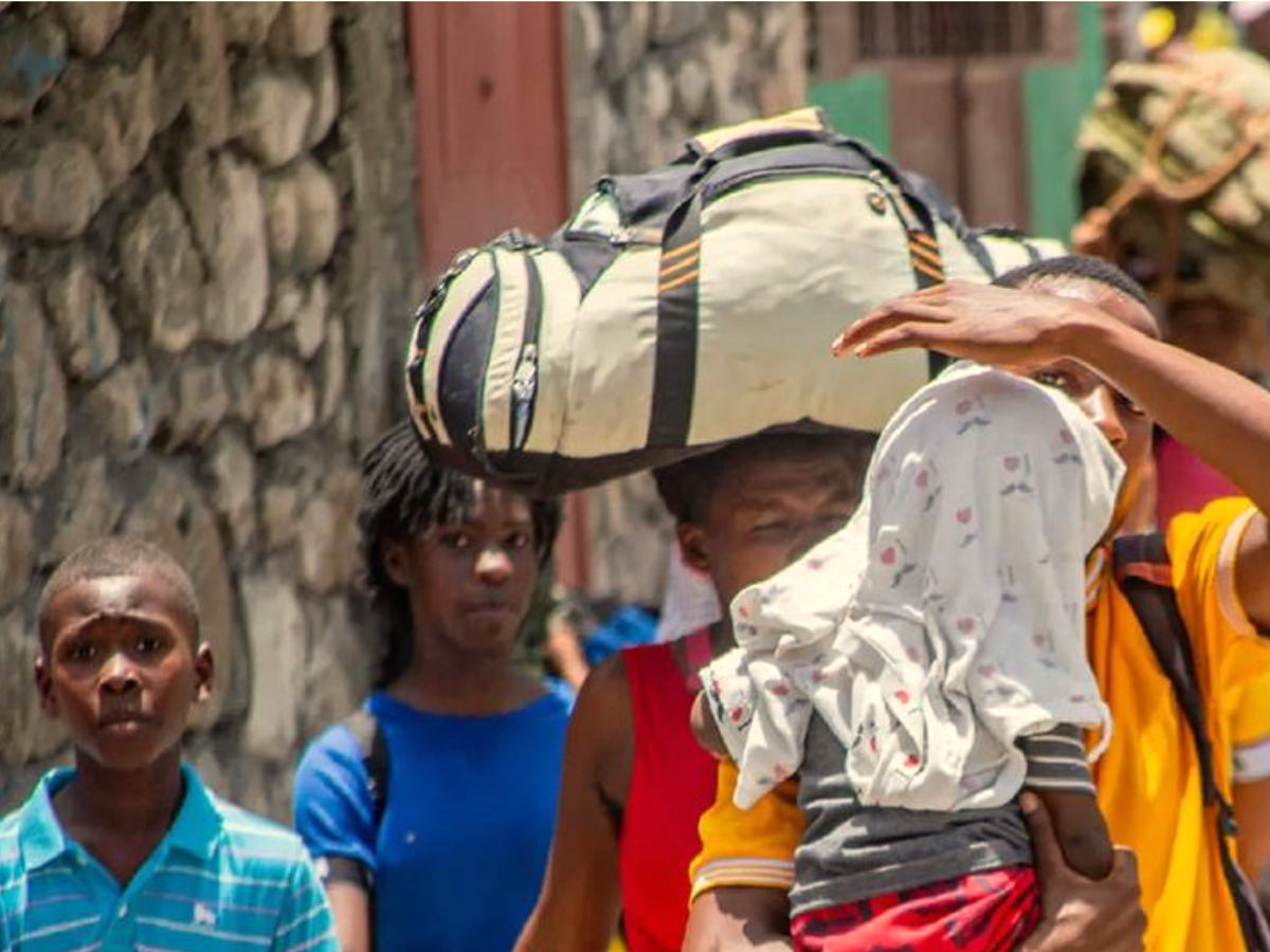 Families in Haiti carry their possessions as they flee homes for safety.