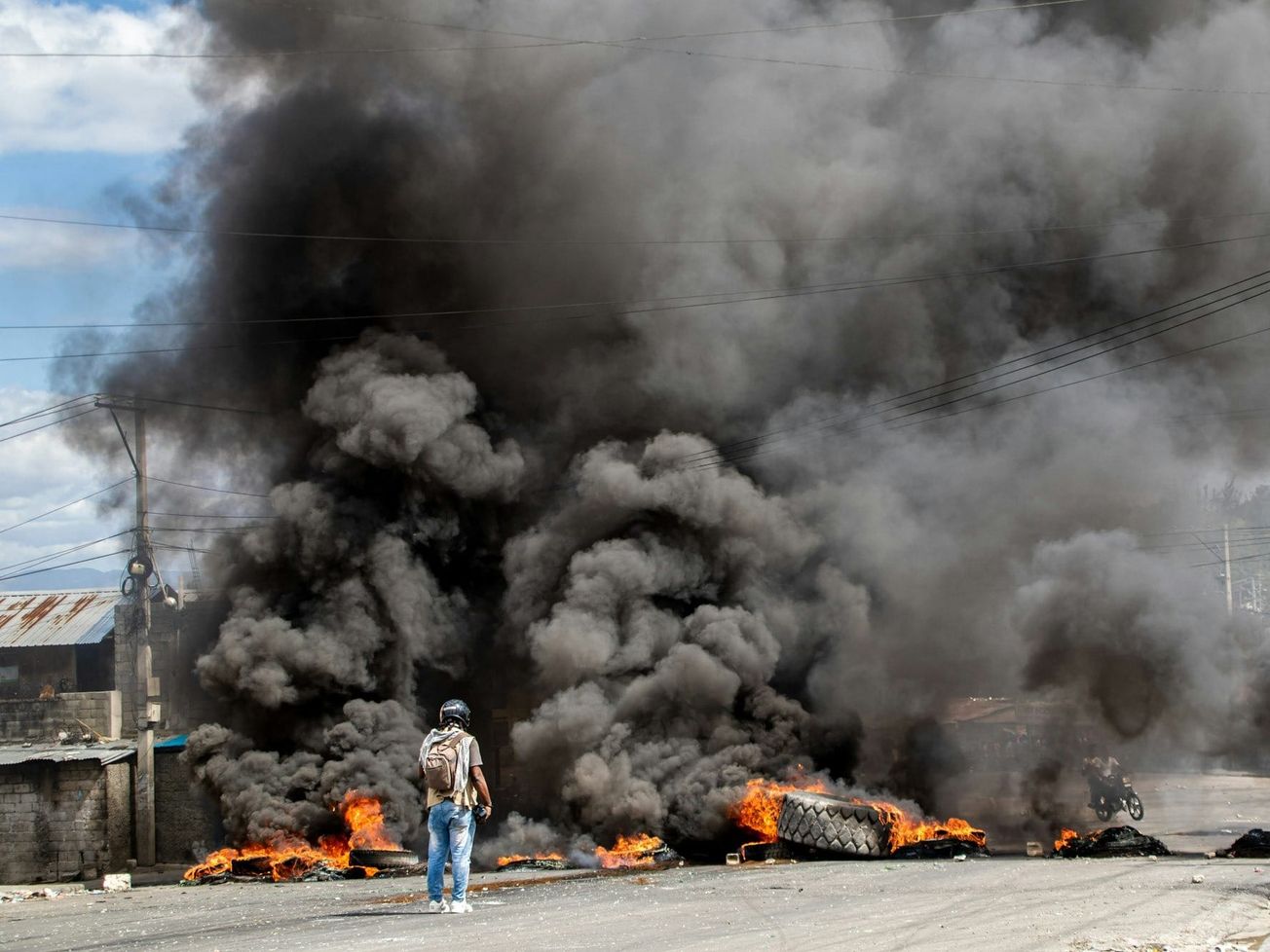 A reporter gets video of a burning barricade in Haiti during a protest.