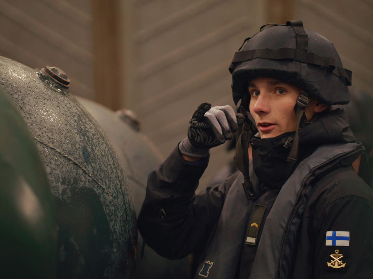 A Finnish Navy crew member stands beside a row of mines in Nov. 2024 during Exercise Freezing Winds.