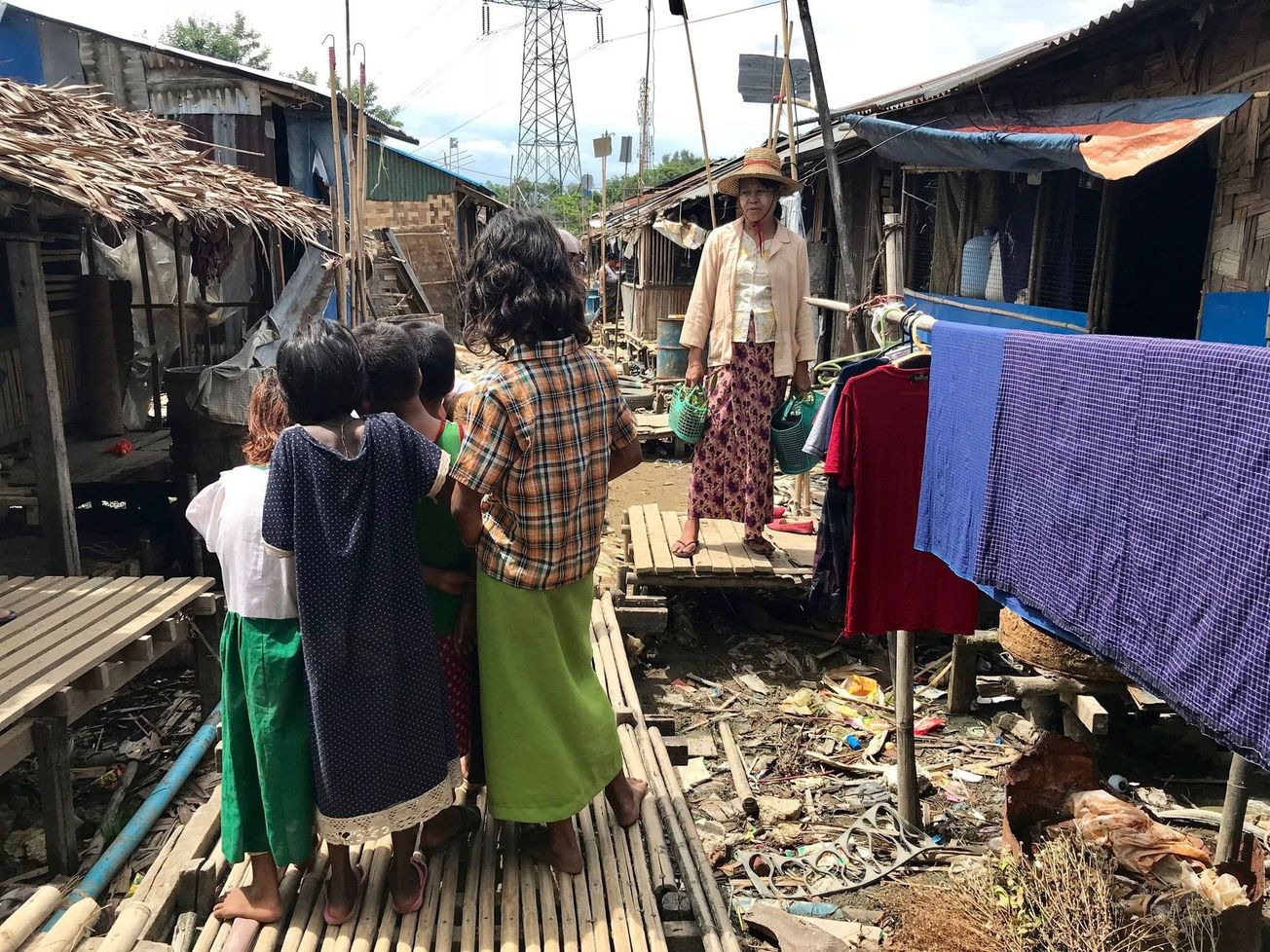 Children standing on an elevated bamboo-walkway built to protect against flooding in Yangon, Myanmar.