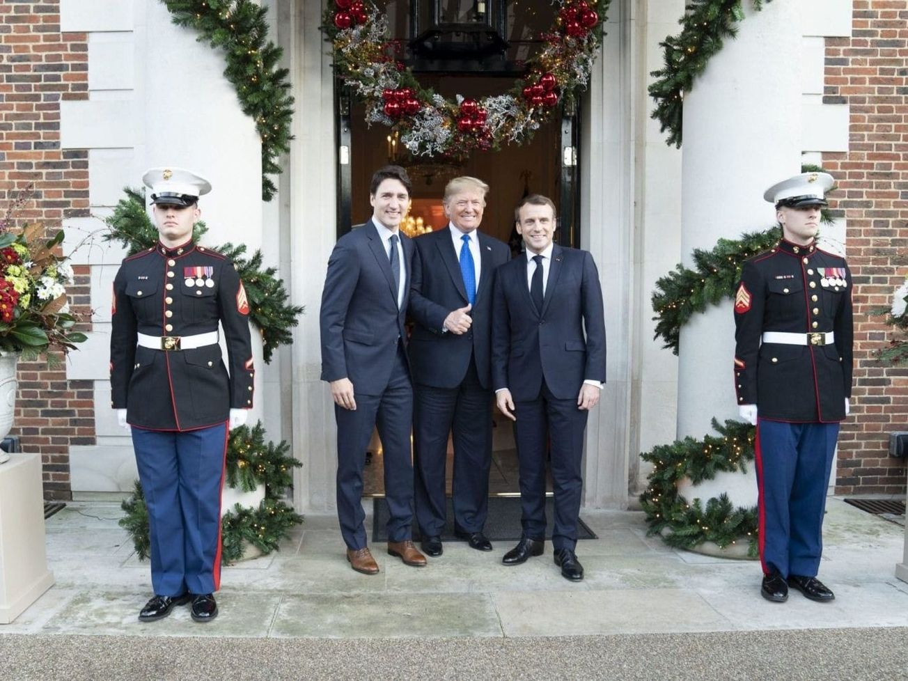 Canadian Prime Minister Justin Trudeau, left, and French President Emmanuel Macron, right, mask their conflicts with U.S. President Donald Trump while posing for a photo.
