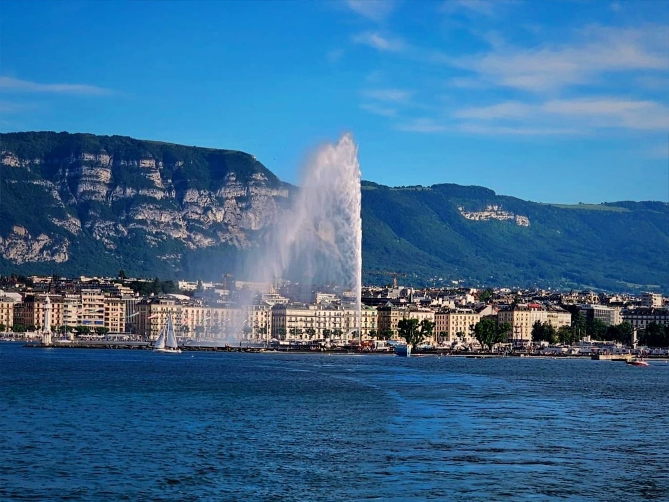 The Jet d'Eau fountain shoots up water before Geneva's skyline and Mont Salève