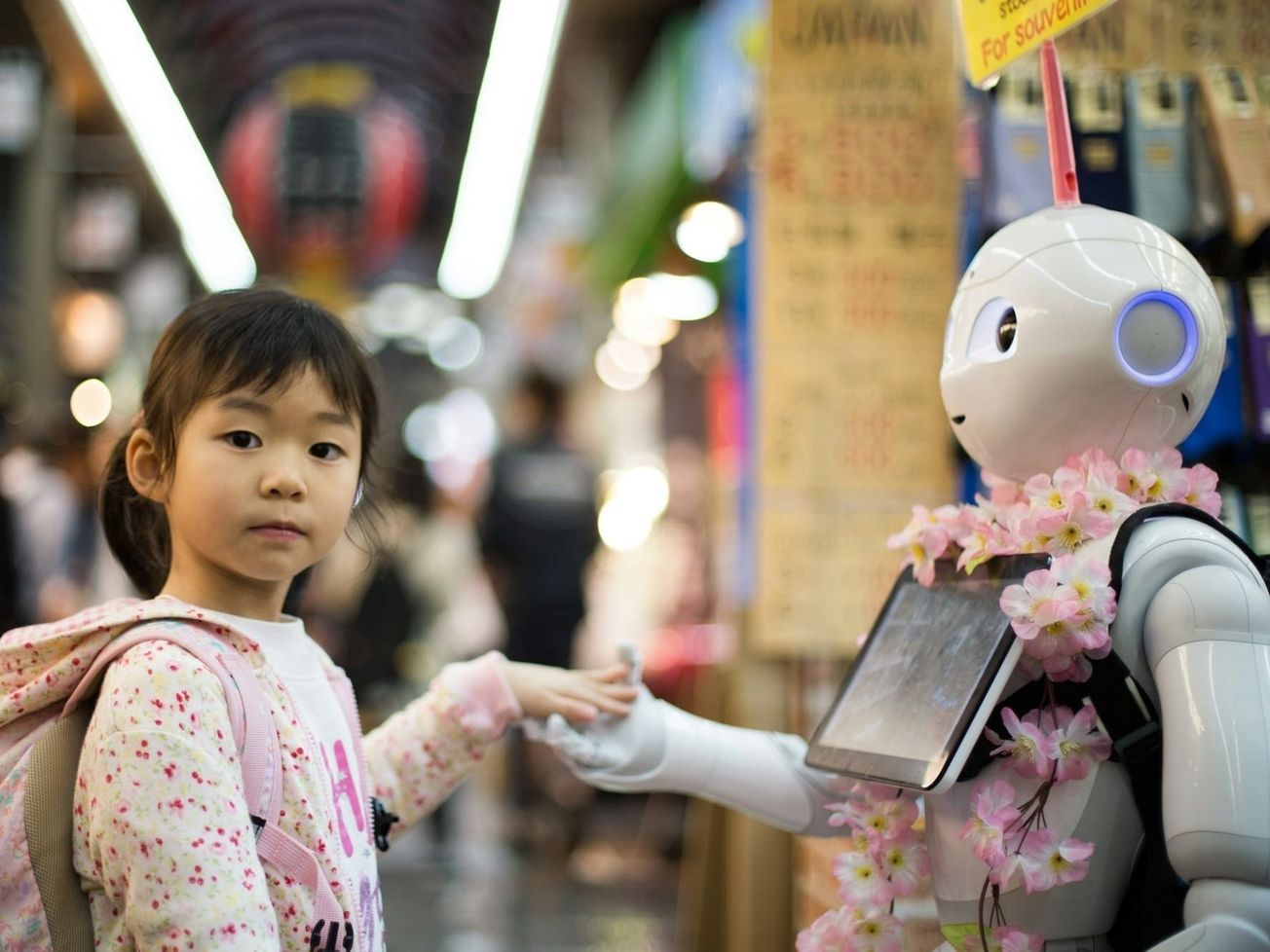 A girl makes friends with a robot at a market in Osaka, Japan.