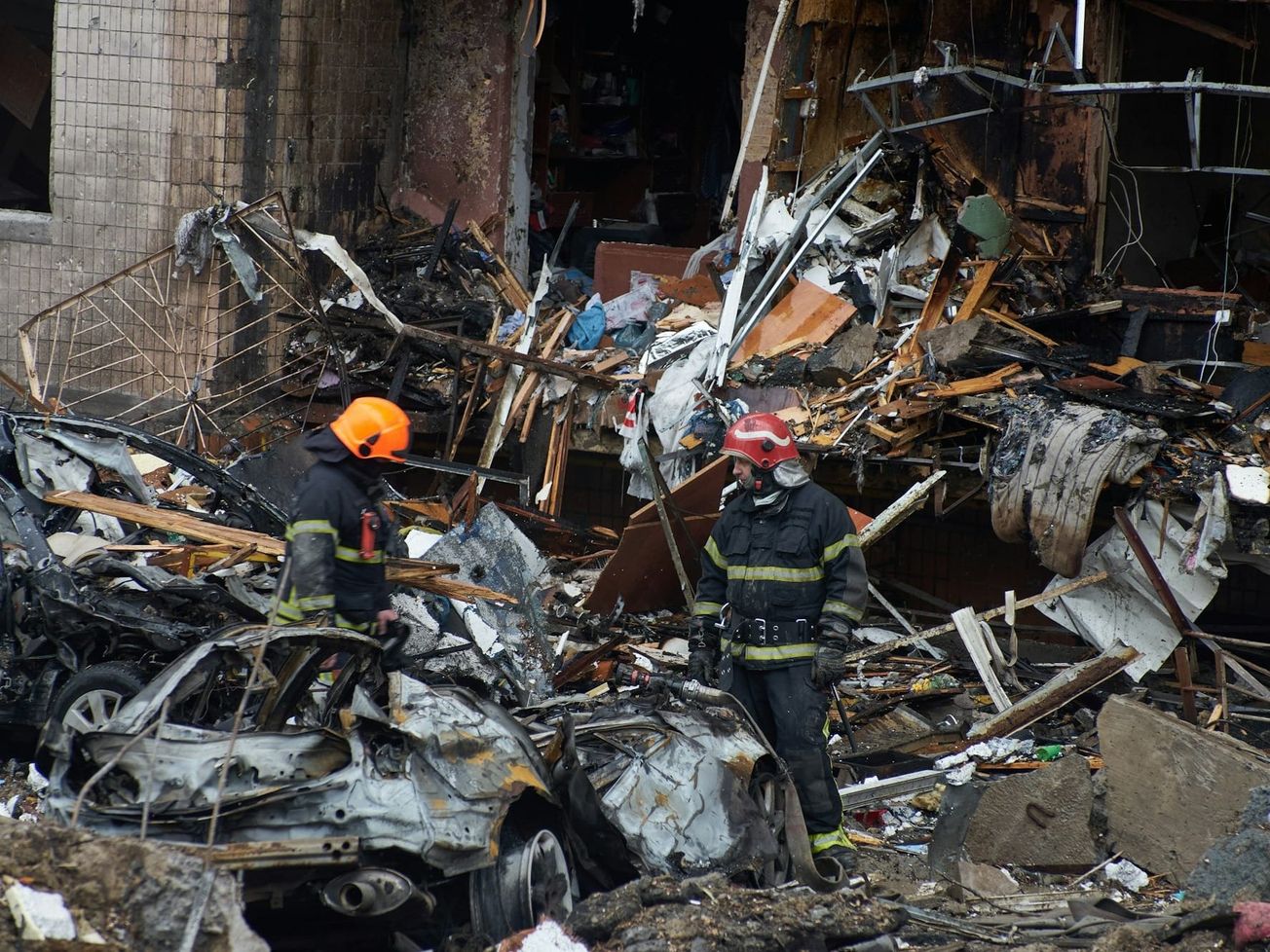 Rescuers and firefighters help Ukrainian civilians and extinguish the fire at a residential building destroyed in an attack with Russian missiles in early 2024. 