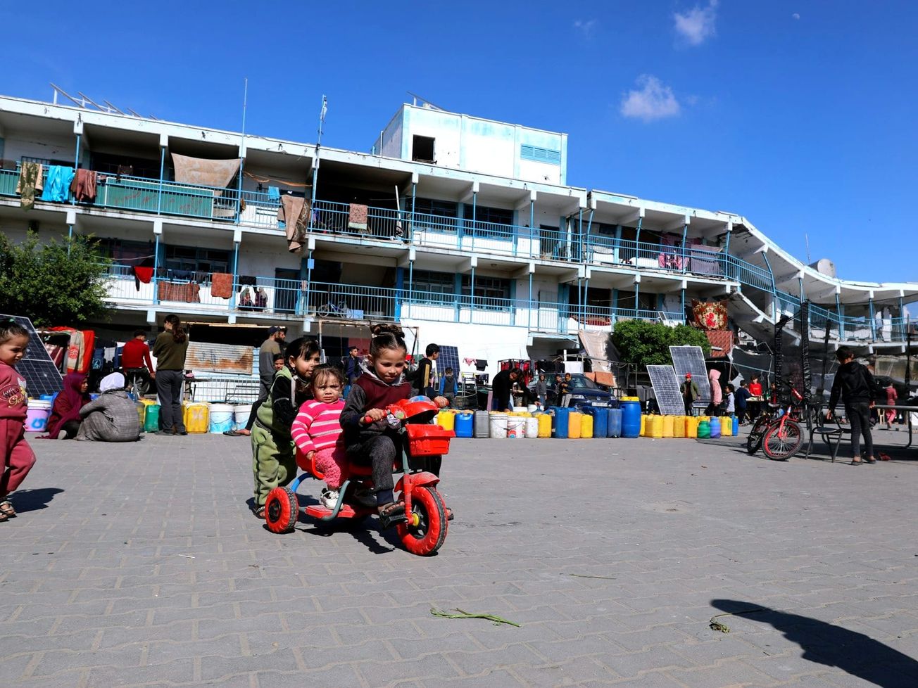 Children play beside a damaged UNRWA shelter.