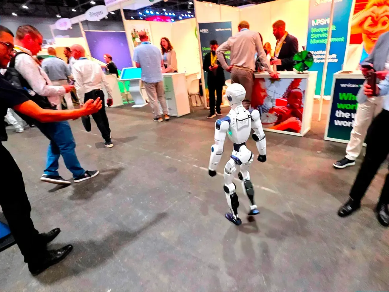 An AI-assisted robot draws attention walking alone among visitors on the opening day of the AI for Good Global Summit in Geneva on July 7, 2026. 